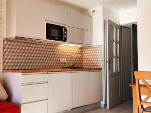 a kitchen with white cabinets and a microwave at Appartement rénové plein sud près des pistes avec parking - FR-1-292-189 in Isola
