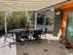 a patio with a table and chairs under a canopy at Zeester 325 in Julianadorp +8 photos