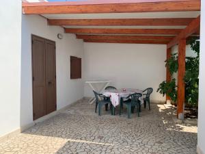 a patio with a table and chairs under a roof at La Depandance in Porto Cesareo