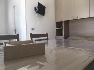 a living room with a table and a tv on the wall at La Depandance in Porto Cesareo