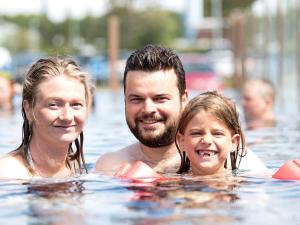 Un homme et une femme dans l'eau dans l'établissement 4 star holiday home in Henne, à Henne