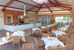a restaurant with white tables and chairs and a chef at Grupotel Club Turquesa Mar in Son Xoriguer
