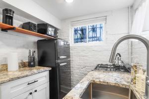 a kitchen with a sink and a black refrigerator at Sojourn Charming Lower Level Studio - Capitol Hill in Washington, D.C.