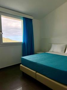 a bedroom with a blue bed and a window at Villa Andrea in Cala Sinzias