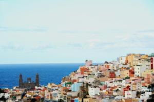 een groep gebouwen op een heuvel naast de oceaan bij NH Las Palmas Playa las Canteras in Las Palmas de Gran Canaria