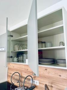 a kitchen with white cabinets with plates and dishes at joli T2 central rénové in Menton +7 photos