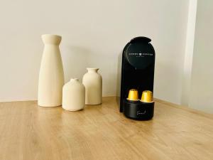 four white vases and a bottle on a wooden floor at joli T2 central rénové in Menton