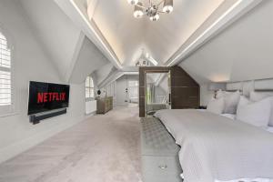 a bedroom with a bed and a tv on the wall at Luxurious Bowdon Mansion by City SuperHost in Bowdon
