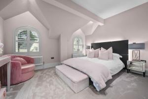 a white bedroom with a large bed and a pink chair at Luxurious Bowdon Mansion by City SuperHost in Bowdon +33 photos