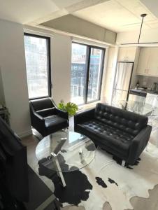 ein Wohnzimmer mit einem schwarzen Sofa und einem Glastisch in der Unterkunft Loft moderne au coeur de Montreal in Montreal