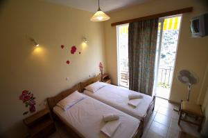 a bedroom with a bed with white sheets and a window at Sunset Crete in Kámbos