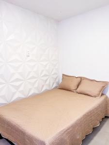 a bed in a bedroom with a white wall at Barra de Jacuipe Village T in Camaçari