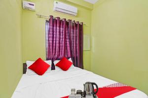 a bedroom with a bed with red pillows and a window at Hotel O Manjiri Restaurant & Lodging in Nagpur
