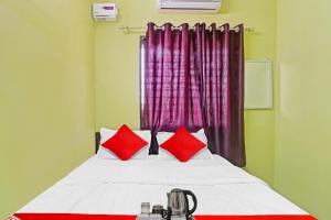 a bedroom with a bed with red pillows and a window at Hotel O Manjiri Restaurant & Lodging in Nagpur
