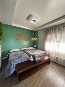 a bedroom with a bed and a green wall at Suíte Juede Platz in Pomerode