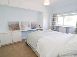 a white bedroom with two beds and a window at Bryn Hyfryd in Conwy