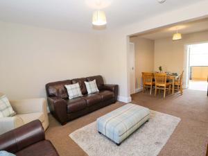 a living room with a leather couch and a table at Bryn Hyfryd in Conwy