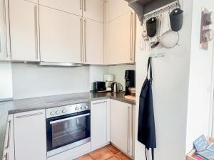 a white kitchen with white cabinets and a refrigerator at Haus Schütz in Grömitz