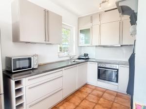 a kitchen with white cabinets and a microwave at Haus Schütz in Grömitz