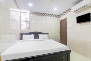a bedroom with a bed and a flat screen tv at Hotel O Aroma Classic Near Nampally Railway station in Hyderabad +41 photos