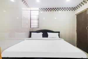a bedroom with a white bed and a window at Hotel O Aroma Classic Near Nampally Railway station in Hyderabad