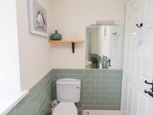 baño con aseo y azulejos verdes en Hasting Dairy, en Seahouses 23 fotos más