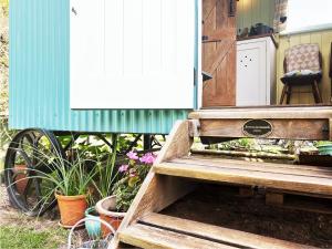 a wooden bench in front of a house with flowers at The Hollies Shepherds Hut by The Suffolk Cottage Collection in Sutton