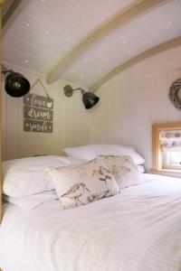a bed with white sheets and pillows in a room at Herbie's Shepherd's Hut - Wellness & Hot Tub in Bottesford