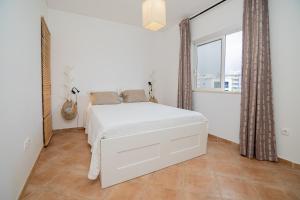 une chambre avec un lit blanc et une grande fenêtre dans l'établissement Alvor Prime BeachStudio, à Alvor