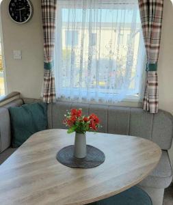 a table with a vase with red flowers on it at The bestwick golden sands in Kinmel Bay