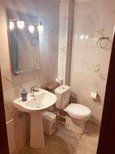 a white bathroom with a toilet and a sink at Babos Holidays in Ammoudia +19 photos