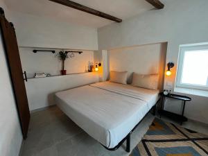 una camera da letto con un letto bianco e una finestra di Vista do Alentejo Rooftop at House near the lake a Torrão
