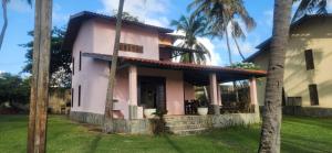 een roze huis met palmbomen ervoor bij Villaggio Lagoa Das Palmeiras in Aquiraz