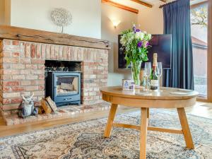 a living room with a brick fireplace and a wooden table at Landers Mews in Trunch