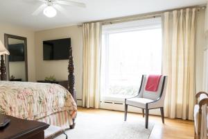 a bedroom with a bed and a chair and a window at Audubon Acres l pool table & outdoor dining in Benton Harbor