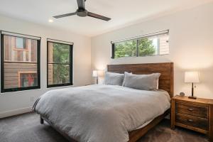 a bedroom with a large bed with two windows at 120 Cedar Drive, Slopeside 4BR Townhome with Mountain Views & Hot Tub in Winter Park