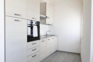 a kitchen with white cabinets and a stove top oven at Bilocale Vega-Intero appartamento ad uso esclusivo by Appartamenti Petrucci by Appartamenti Petrucci in Foligno