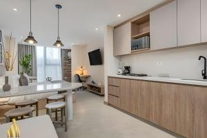 a kitchen with white cabinets and a kitchen island with stools at Solei Loft 202 - Chic Studio with AC in El Poblado