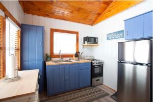 una cucina con armadi blu e frigorifero in acciaio inossidabile di 4 Beachfront Cottages - New Bathrooms and Roofs a Lincoln Junction