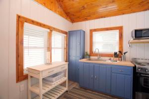 a small kitchen with blue cabinets and a sink at 4 Beachfront Cottages - New Bathrooms and Roofs in Lincoln Junction