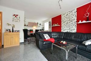 a living room with a black couch and a red wall at Apartment Bergen auf Rugen 1 in Bergen auf Rügen