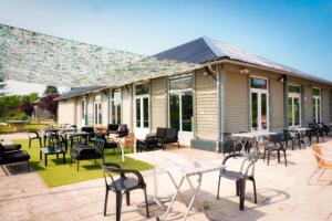 a patio with tables and chairs in front of a building at Ushuaïa Villages-Domaine de Scott in Montigny-en-Morvan