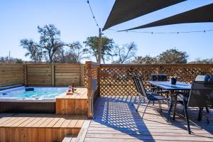 a deck with a hot tub and a table and an umbrella at Contained In Gruene -River Edition- Hot Tub in New Braunfels
