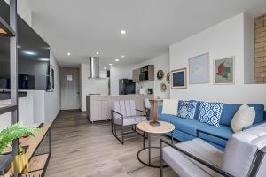 a living room with a blue couch and a kitchen at Class 48 apto. 1404 - Vistas modernas de la ciudad / AC in Sabaneta