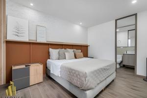 a bedroom with a large bed and a bathroom at Class 48 apto. 1404 - Vistas modernas de la ciudad / AC in Sabaneta