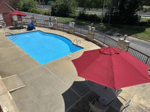 a person with a red umbrella next to a swimming pool at Red Roof Inn & Suites Cornelius - Lake Norman in Cornelius