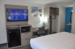 a hotel room with a bed and a desk with a television at Clarion Inn in Greenville