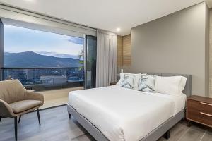 une chambre avec un lit blanc et une grande fenêtre dans l'établissement Class 48 Apt. 2301 - Luces de ciudad/Loft/Balcón priv, à Sabaneta