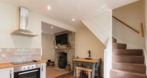 un salon avec un escalier et une cheminée en pierre dans l'établissement Vern Dale Cottage, Erwood, River Wye, Builth Wells, à Builth Wells