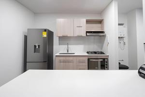 a white kitchen with a refrigerator and a sink at Class 48 Apt. 2302 - Íntimo loft con balcón privado in Sabaneta